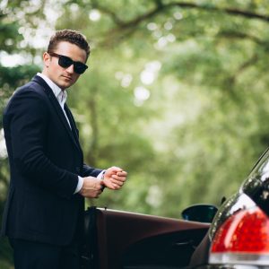 Homem bem vestido em frente ao seu carro de luxo